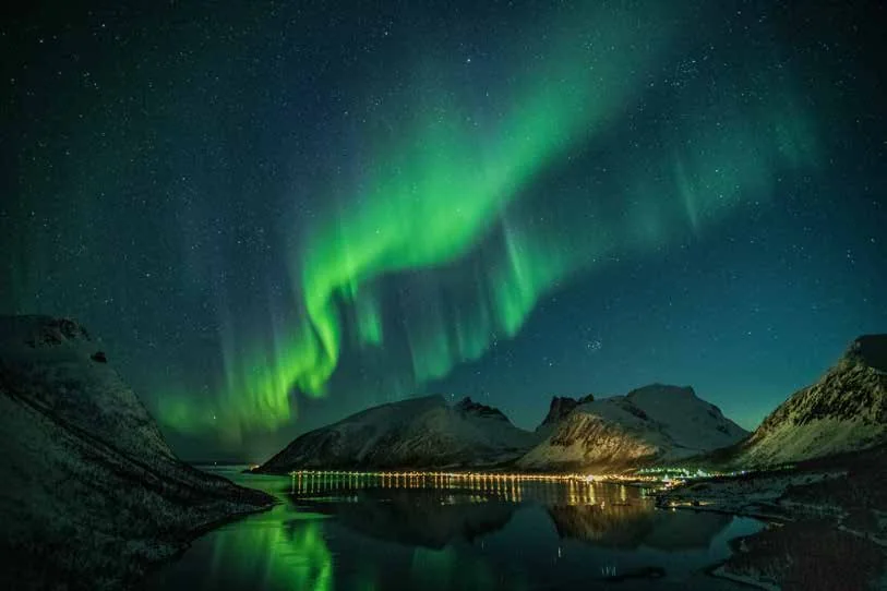 Aurora boreal sobre montañas y un lago