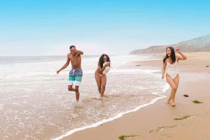Tres viajeros riendo en la orilla de una playa